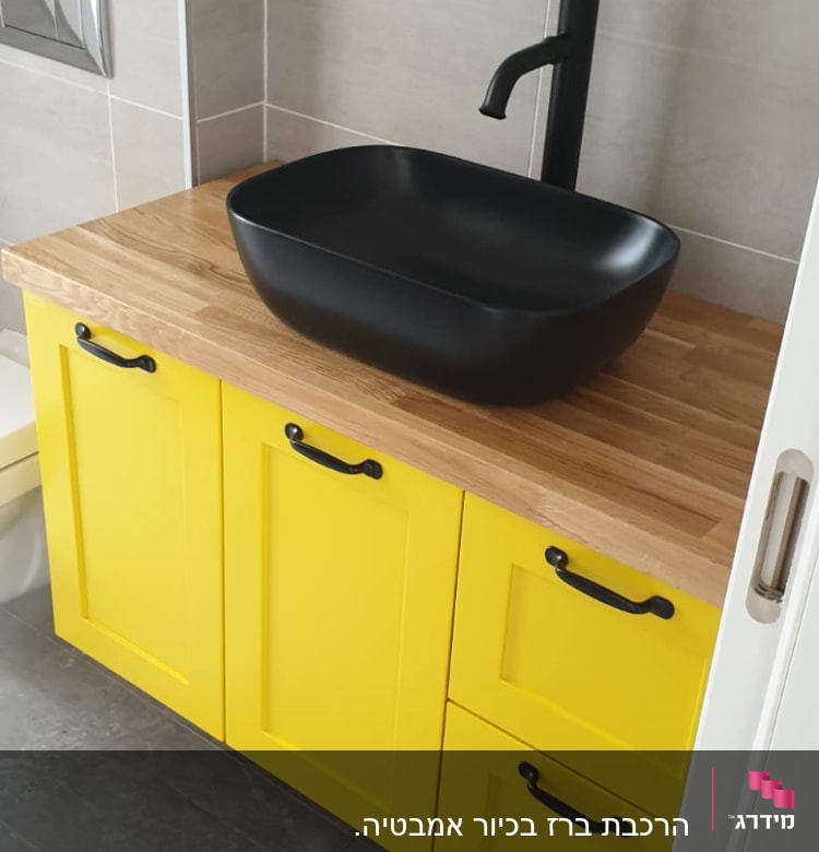 כיור שחור עם ברז על ארון צהוב